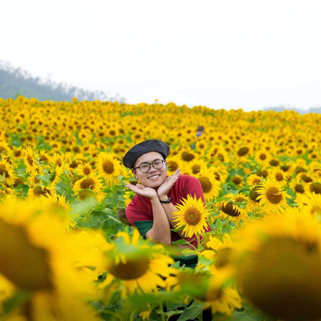 man smiling in a large field of sunflowers