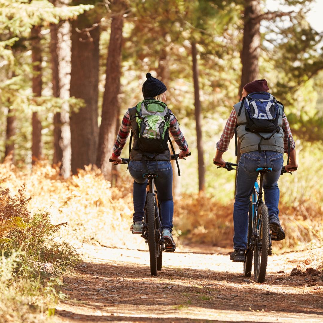 A couple mountain biking a trail in the woods 